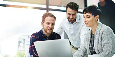 Group of professionals collaborating on a laptop in an office setting.