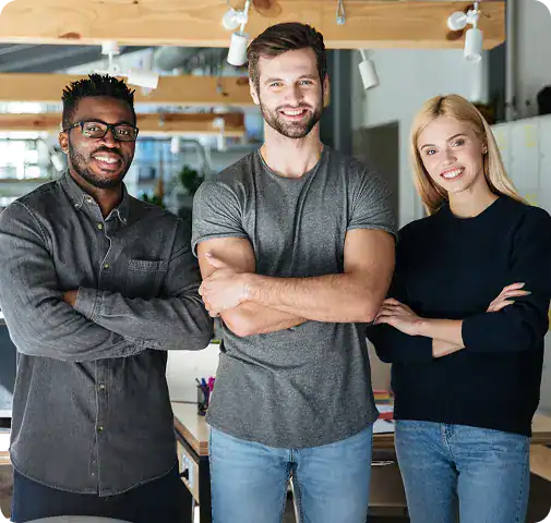 Team of three smiling colleagues standing together in a contemporary workspace.